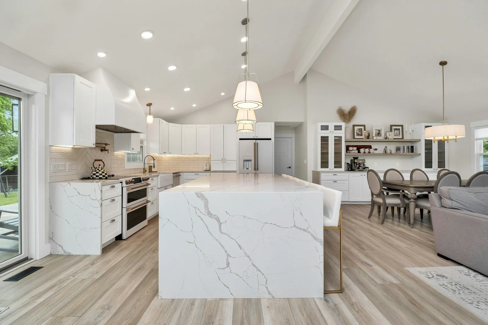 White kitchen with marble island and light wood floors