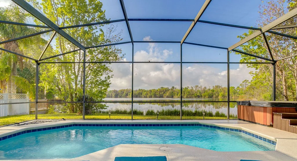 Resort community pool with palm trees under a blue Florida sky